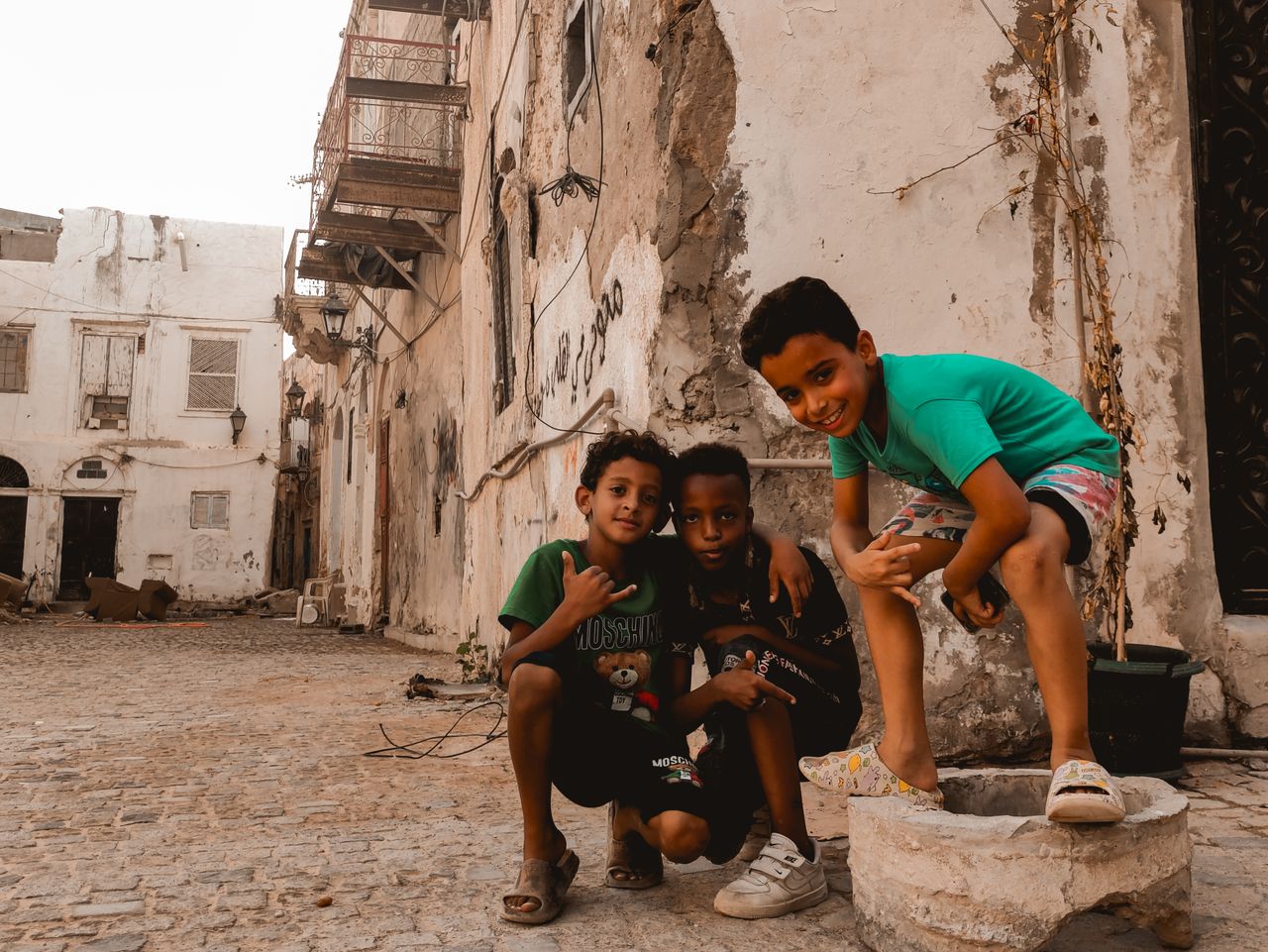 Three children enjoying a playful moment in the historic streets of Tripoli, Libya.