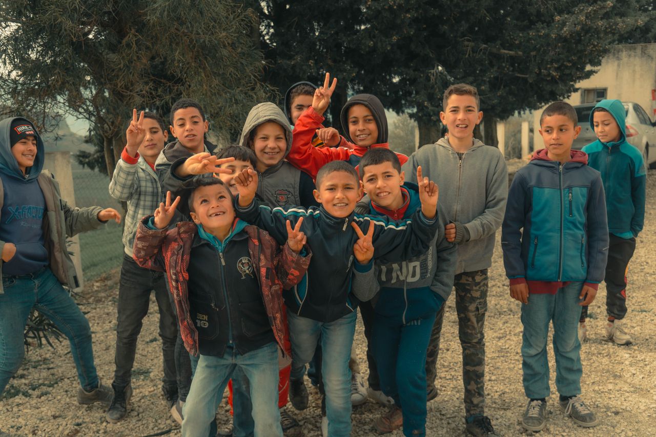 A joyful group of boys posing and playing outdoors, expressing happiness and friendship.